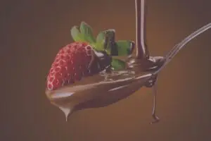 Rode aardbei op een lepel met stromende en druipende chocolade chocolade en een