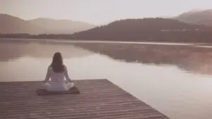 Vrouw zittend op een steiger aan het water.